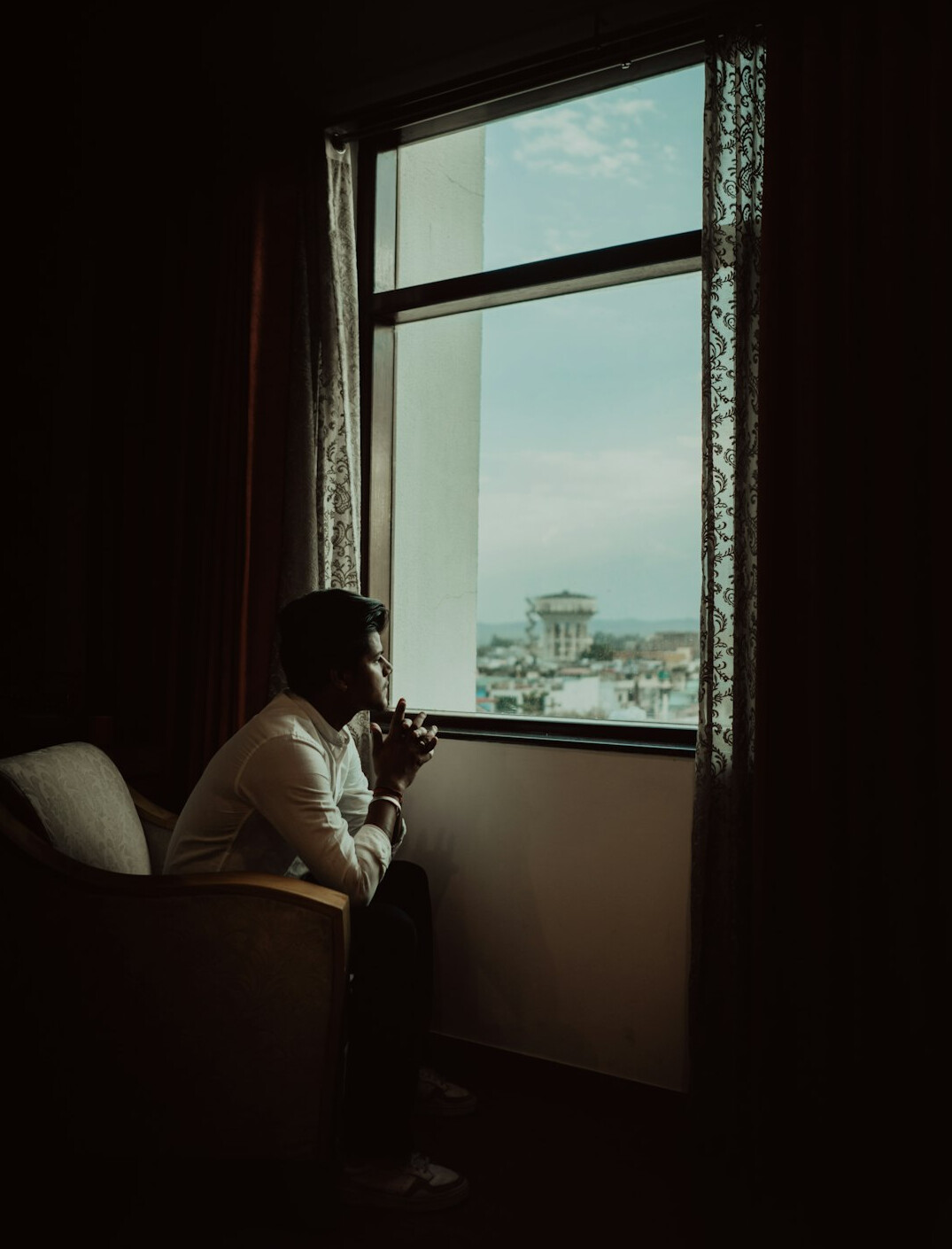 Brazilian man writing in a journal near a window, reflective mood